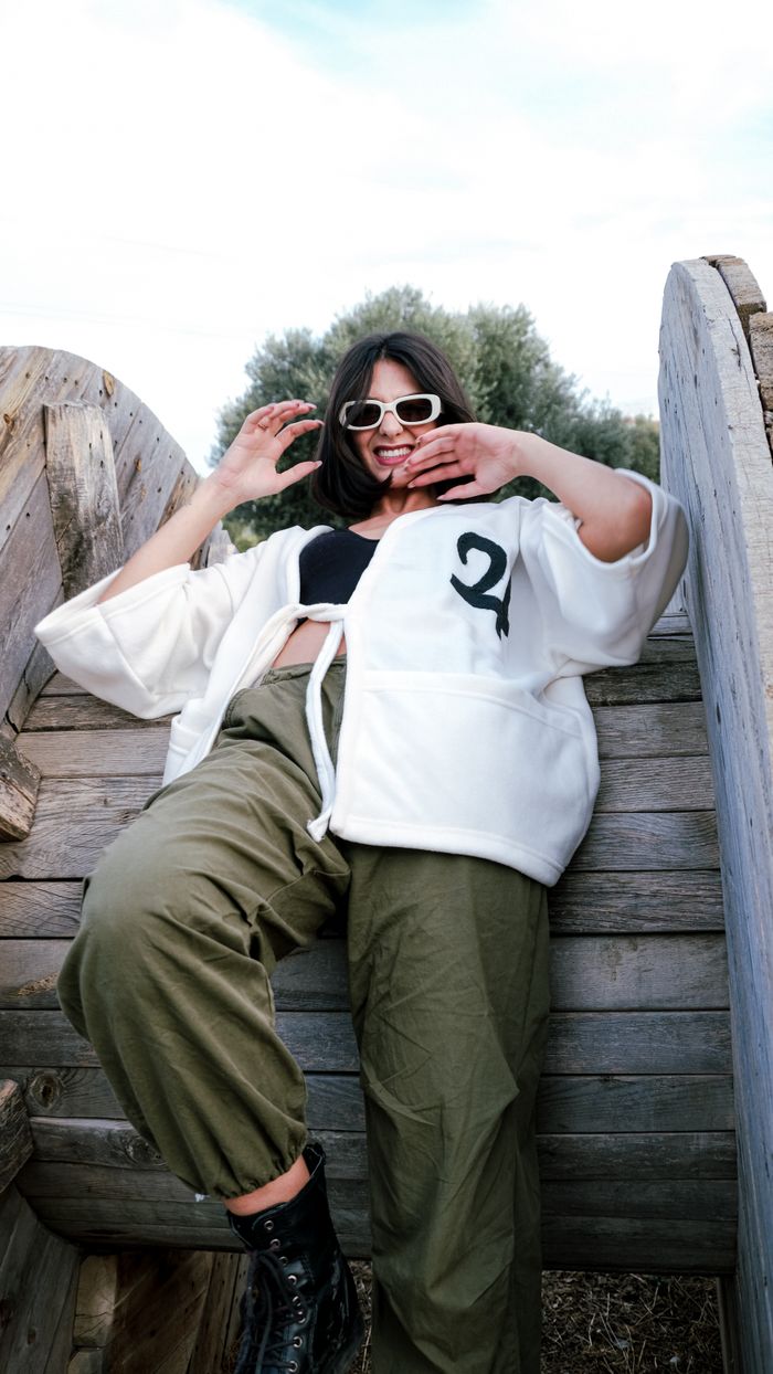 Trendy woman in sunglasses posing against a wooden backdrop, exuding confidence.
