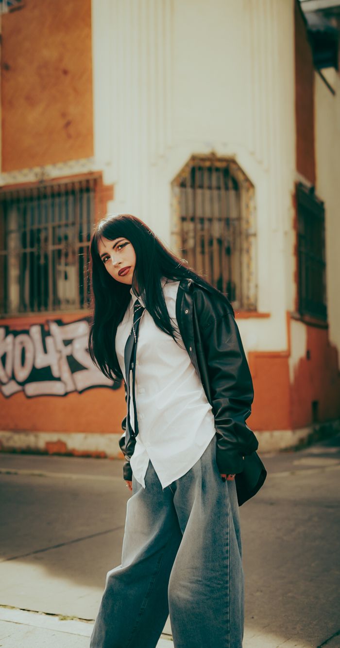 Stylish woman posing in casual wear against graffiti wall in urban setting.
